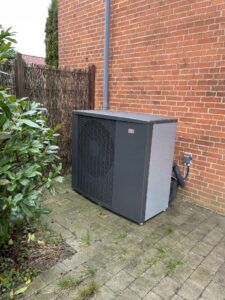 Outdoor heat pump beside brick house wall